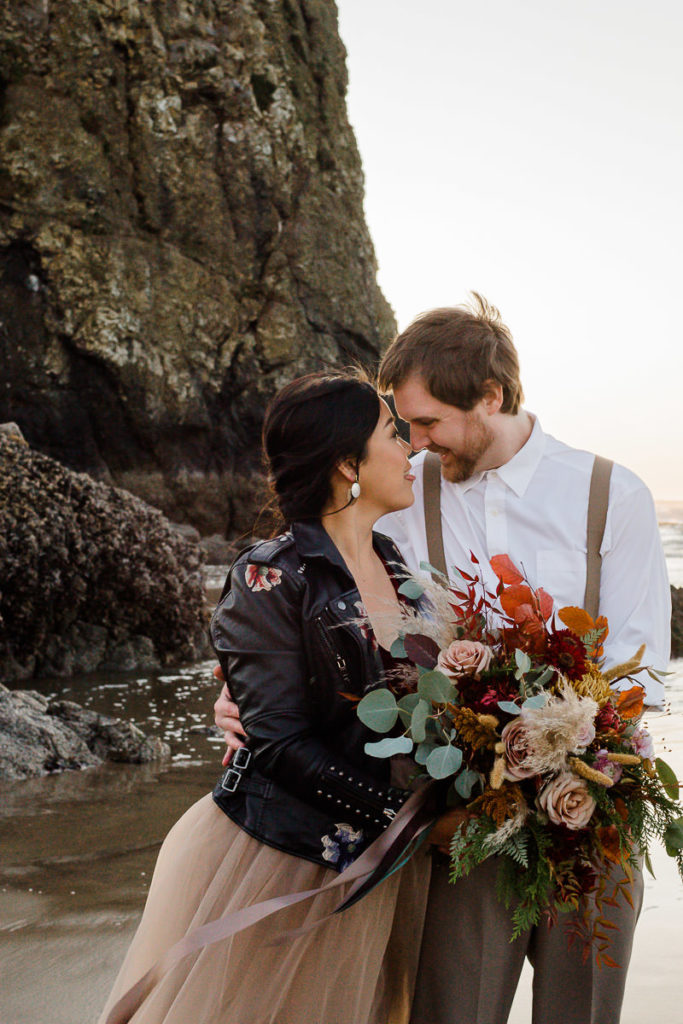 bride and groom together in front of haystack rock