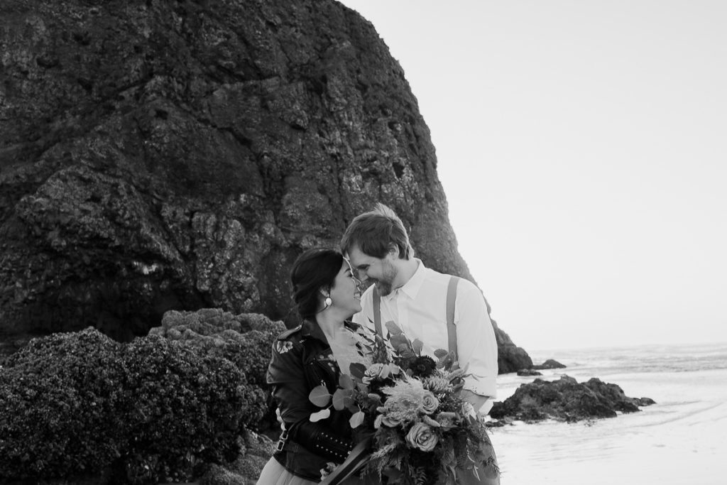 bride and groom together in front of haystack rock