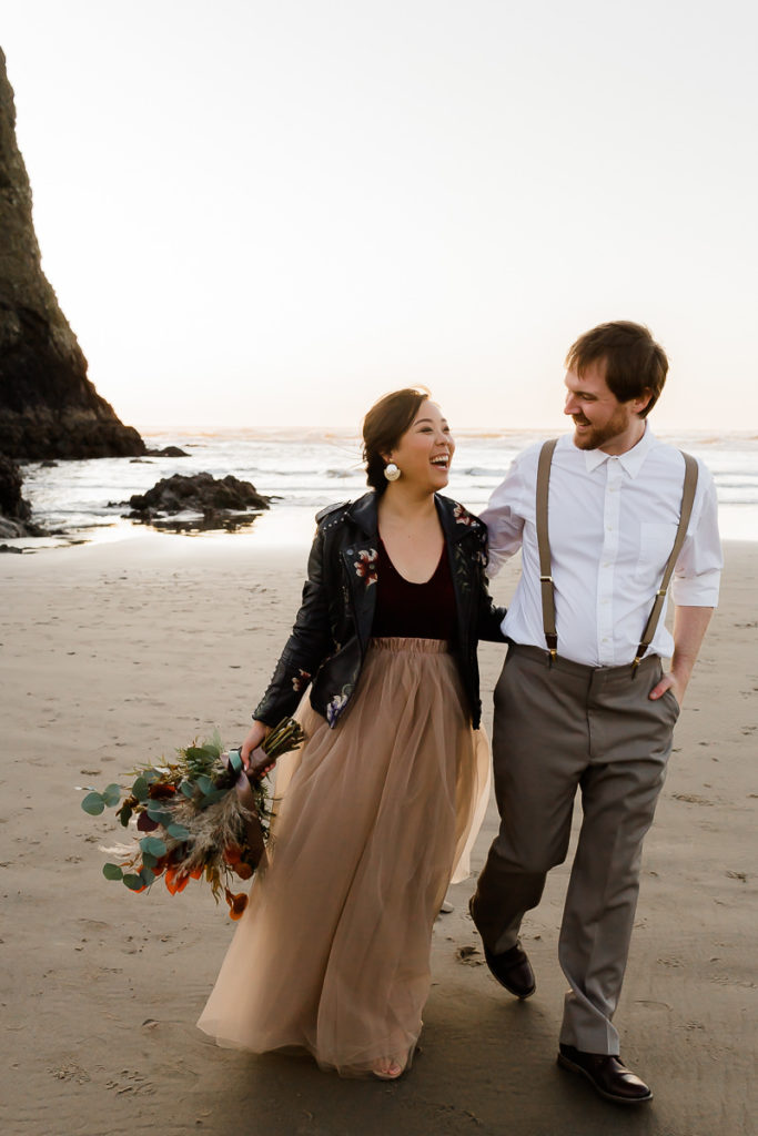 bride in leather jacket and groom walking at cannon beach
