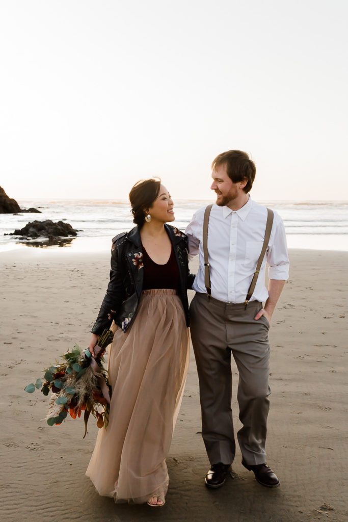 bride in leather jacket and groom walking at cannon beach