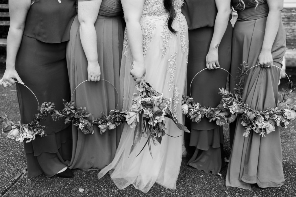 bride and bridesmaids in mixed red gowns with floral rings