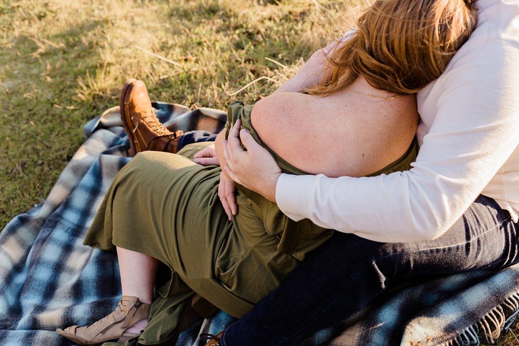 Couple sitting on blanket on the hilld side cuddling as the sun sets Government Cove Oregon Engagement Photography captured by Oregon Engagement Photographer Simply Wandering Photography 
