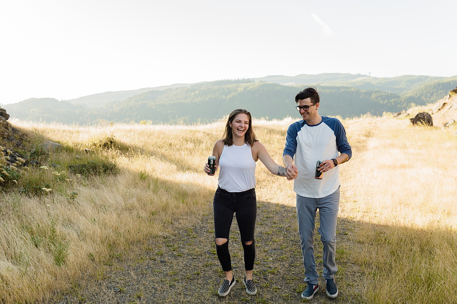 Couple walking on field holding hands with mountain behind them