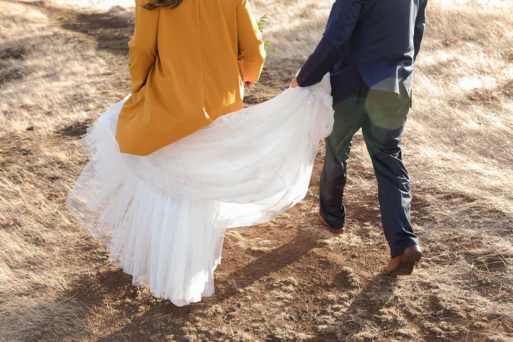 Bride wearing a jacket with wedding dress and groom holding the train