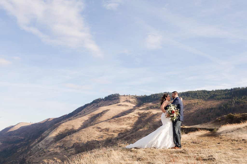 Bride and Groo holding each other with floral bouquet on the mountain top
