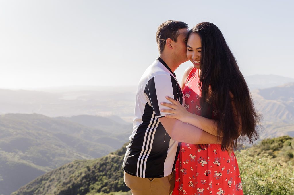 Man kissing woman on the cheek with a mountain view Santa Barbara Proposal Photography captured by Oregon Engagement Photographer Simply Wandering Photography 