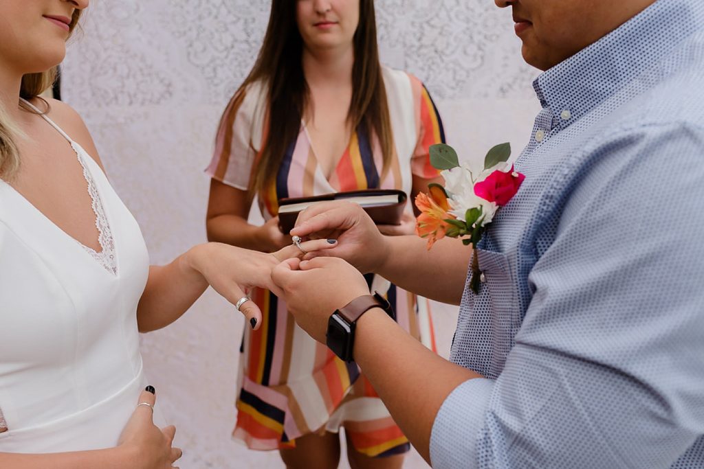 Groom putting ring on Bride's finger