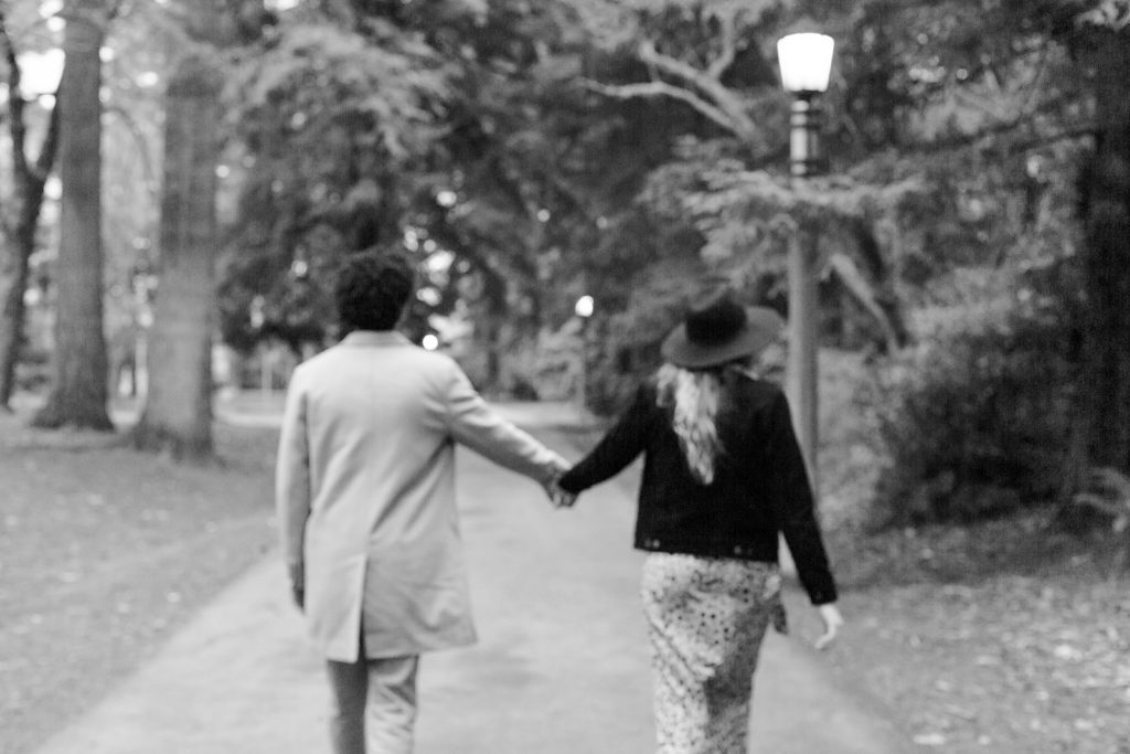 B&W of couple extending arms to hold hands while walking