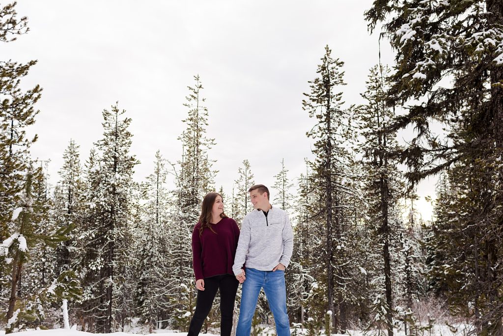 Wide shot of Couple holding hands standing in snowy forest
