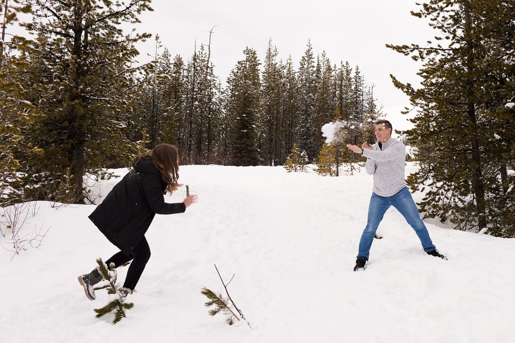 Man throwing snowball at lady