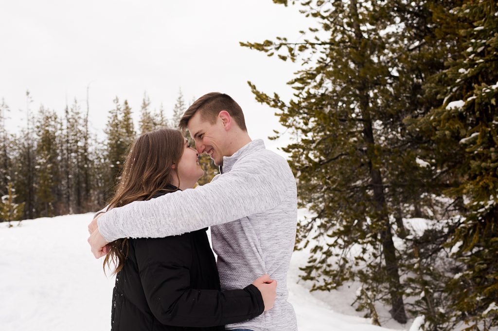 Couple holding each other close in the snow forest