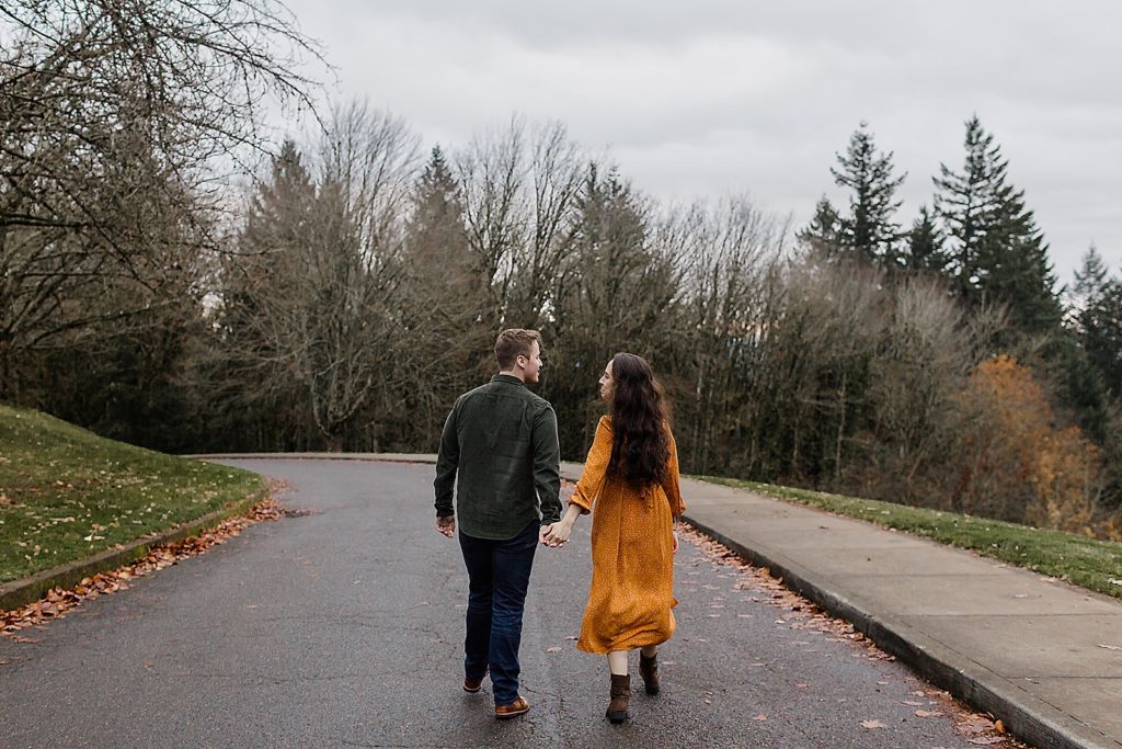 Couple holding hands looking at each other walking on the road