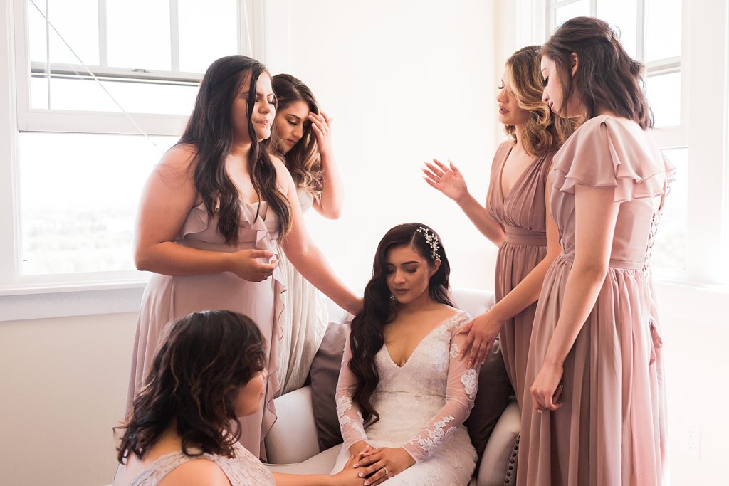 Bride sitting and Bridesmaids praying over her