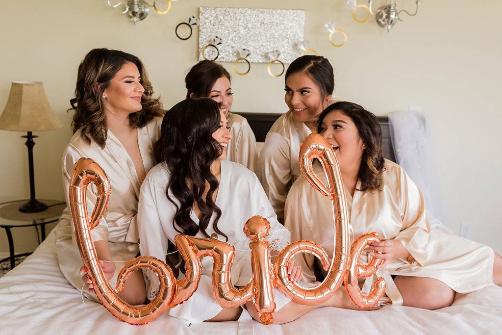 Bride and Bridesmaids holding "bride" balloon before getting ready