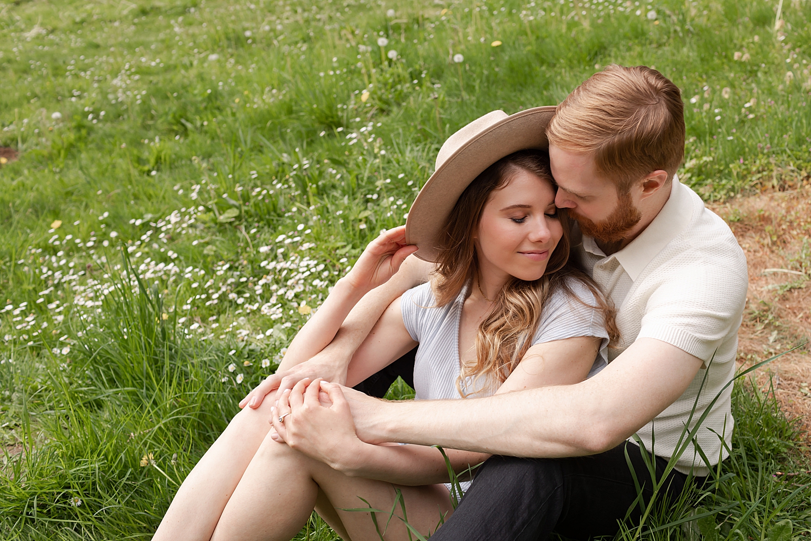 Man holding woman and sitting on grassy field