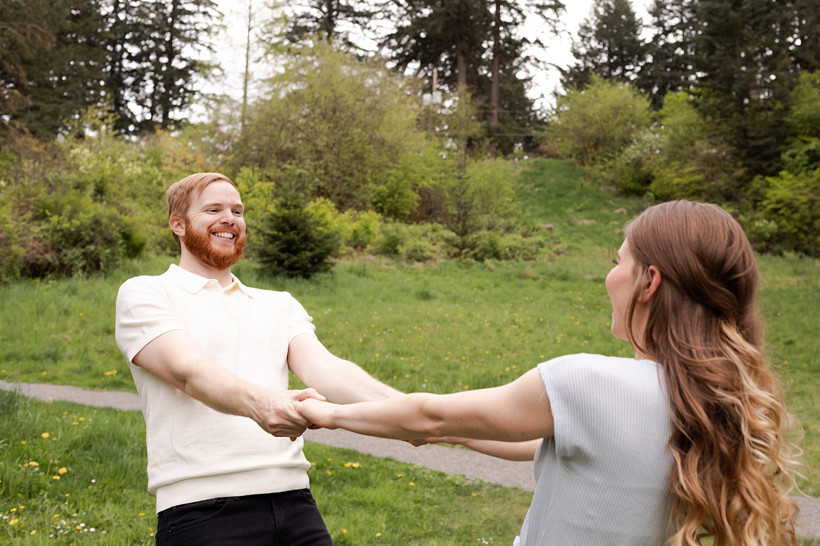 Couple holding hands and spinning on green grass field
