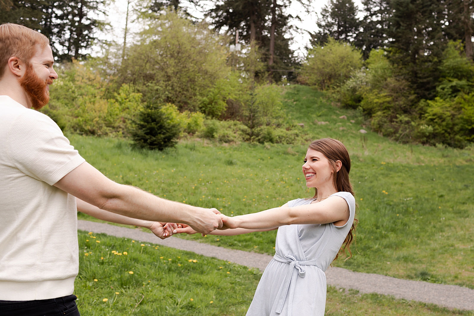 Couple holding hands and spinning on green grass field