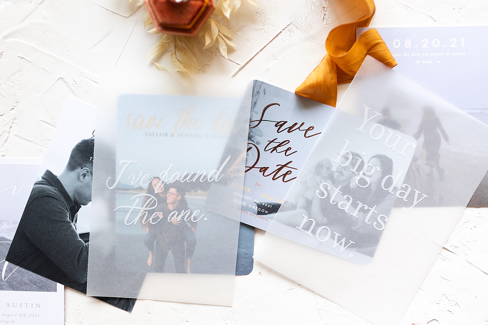 variety of save the date cards under vellum overlays