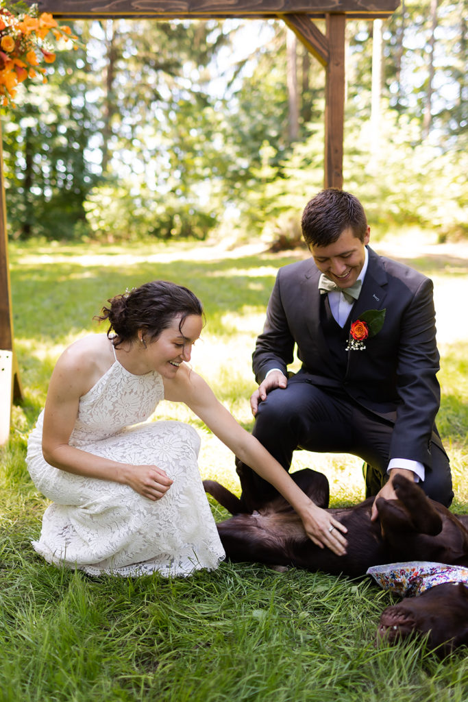 bride in lace halter dress smiling at dog