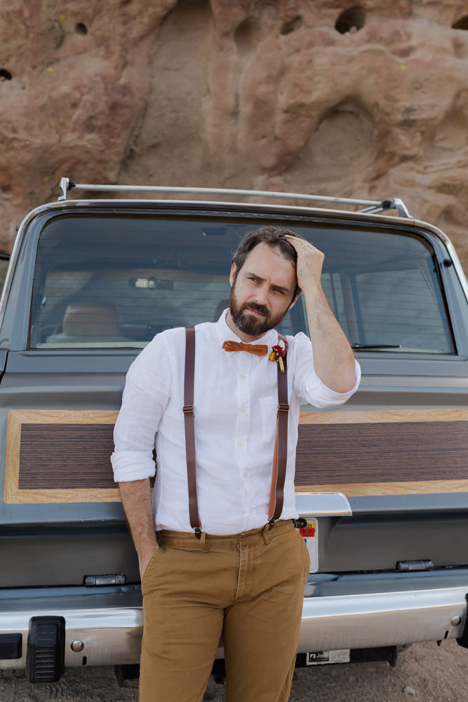 groom leaning against classic jeep wagoneer