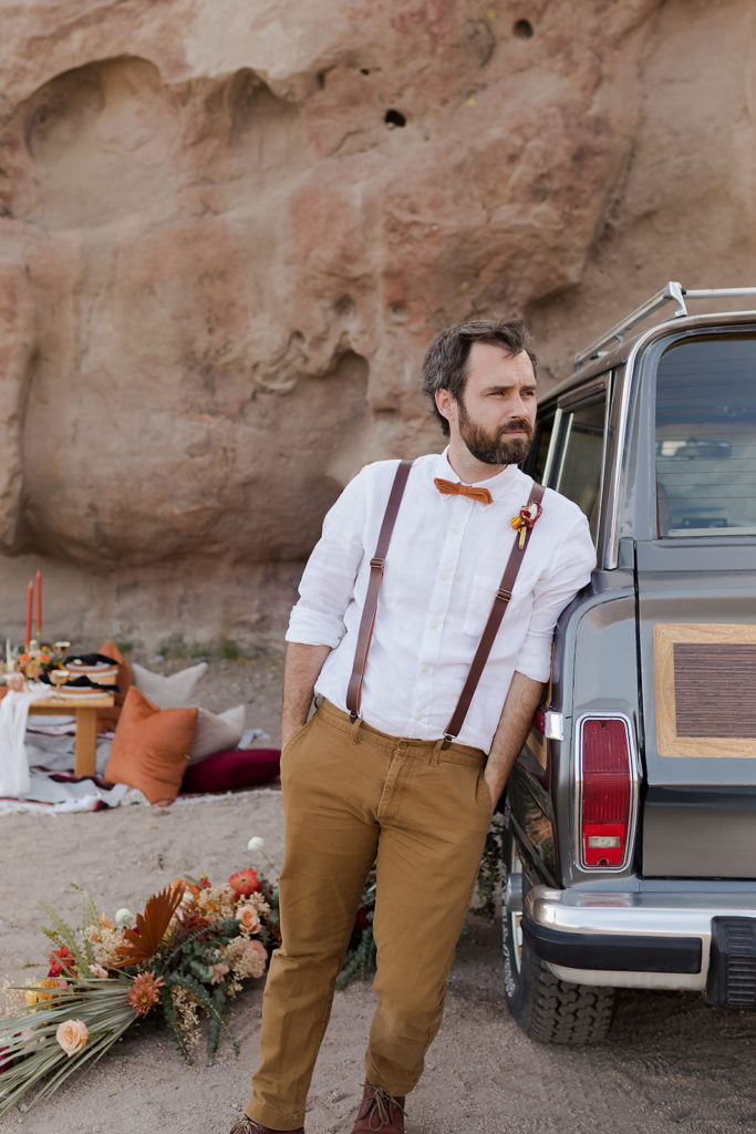 groom leaning against classic jeep wagoneer